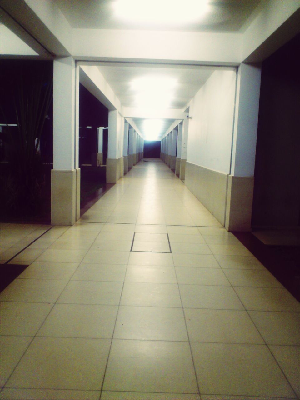 indoors, the way forward, corridor, illuminated, tiled floor, flooring, architecture, empty, built structure, diminishing perspective, ceiling, lighting equipment, absence, vanishing point, in a row, walkway, floor, tile, narrow, no people