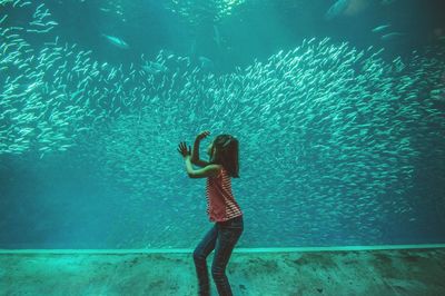 Girl looking at fishes in aquarium