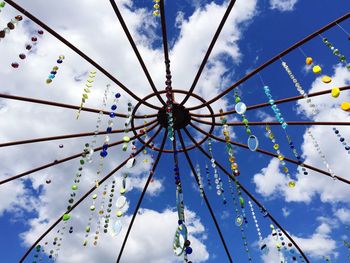 Low angle view of hanging beads against blue sky