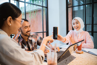 Young woman using mobile phone while standing in cafe