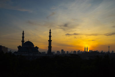 Mosque in city against sky during sunset