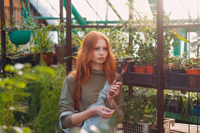 Portrait of beautiful young woman standing against plants