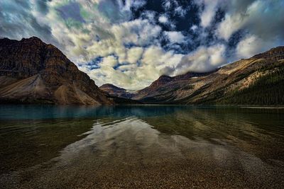 Scenic view of lake and mountains against dramatic sky