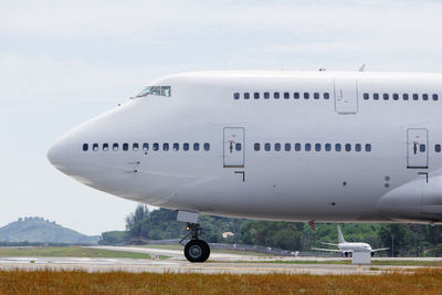Airplane on airport runway against sky