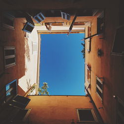 Directly below shot of houses against clear blue sky