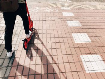 Low section of person riding push scooter on footpath