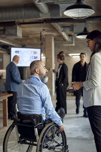 Businessman with disability talking to businesswoman at creative office