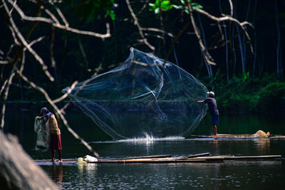 Fisherman throwing net in lake