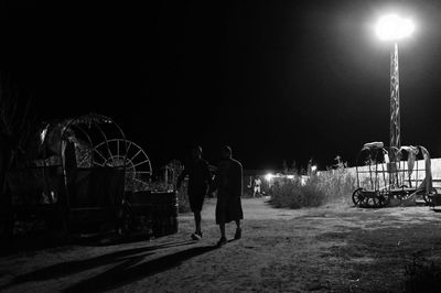 Rear view of man walking on road at night