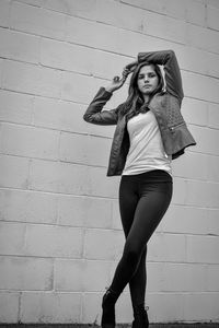 Portrait of young woman standing against wall