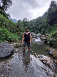 Full length of young man standing on rock against trees