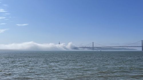 Suspension bridge over sea against sky