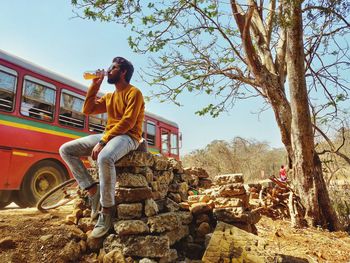 Man sitting in bus against sky