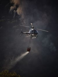 Low angle view of helicopter flying in sky fighting forest fire