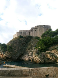 Buildings by sea against sky