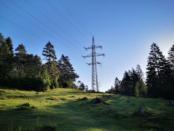 Low angle view of electricity pylon on field against sky