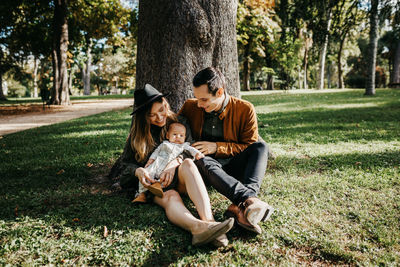 Friends sitting on tree trunk in park