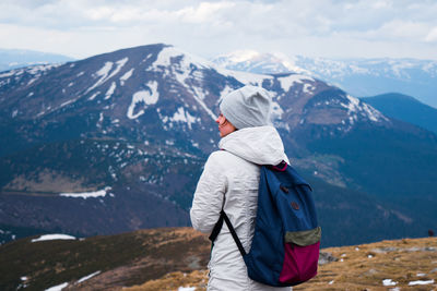 Rear view of woman hiking on mountain during winter