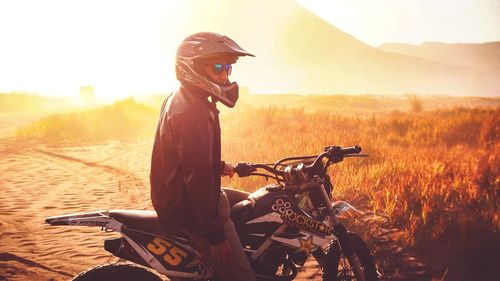 Side view of man riding motorcycle on field