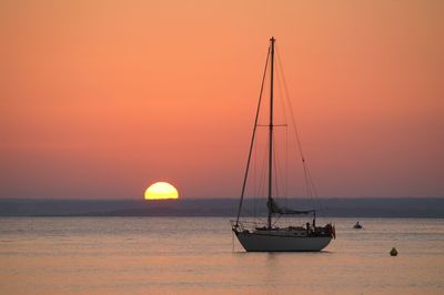 Sailboat on sea against orange sky