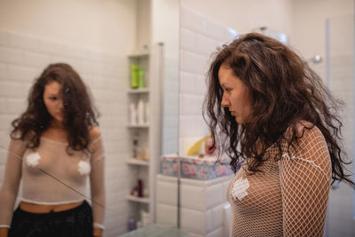 Angry woman standing by mirror at home