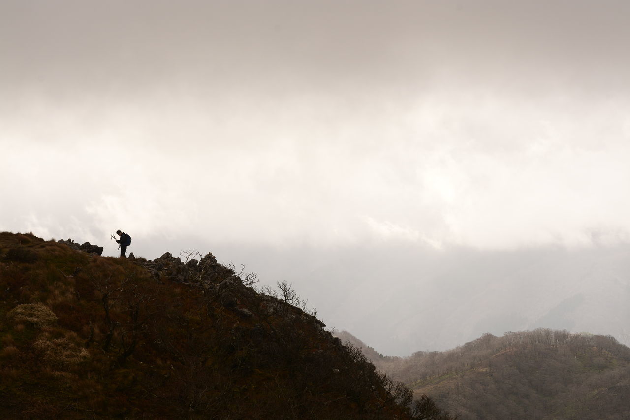 MAN STANDING ON MOUNTAIN
