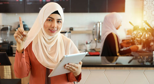 Portrait of a smiling young woman holding camera