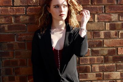 Young woman standing against brick wall