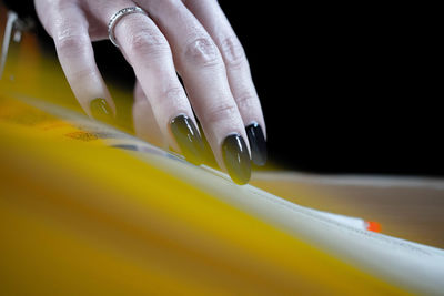 Close-up of human hand holding yellow paper