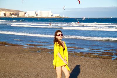 Woman in yellow dress top at beach on sunny day