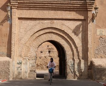 Woman riding bicycle outside historic building