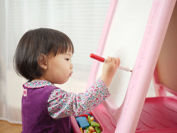 Cute girl writing in whiteboard at home