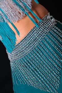 Close-up midsection of woman wearing blue dress against black background