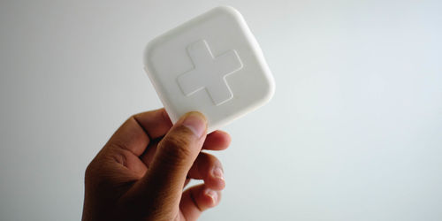 Close-up of hand holding medicine box against white background