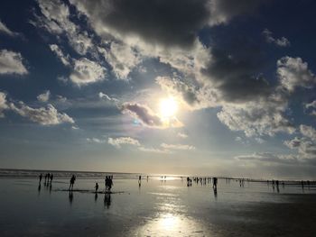 Silhouette people on beach against sky