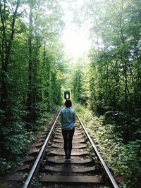 Rear view of man walking on railroad track