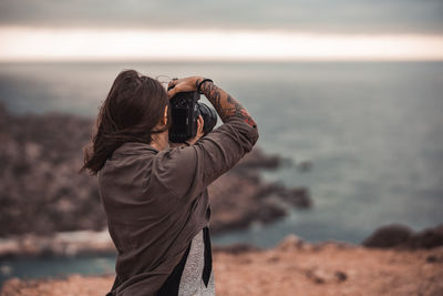 Midsection of man photographing at sea shore