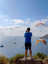 Rear view of man standing in sea against sky