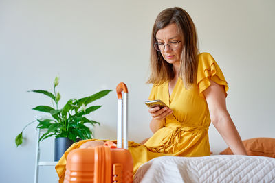 Portrait of young woman sitting on bed at home