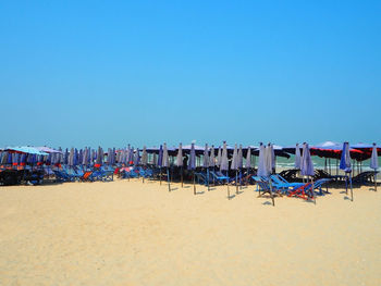 Chairs on beach against clear blue sky