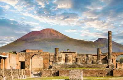 Old ruins with mountains in background against cloudy sky