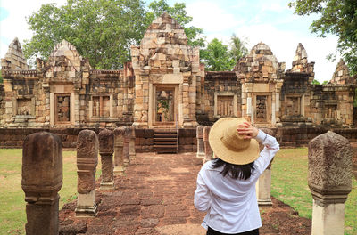 Rear view of woman standing against old ruins