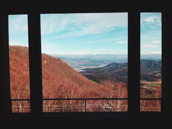 Scenic view of mountains against sky seen through window