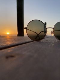 Close-up of sunglasses against sky during sunset