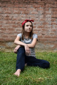 Full length of beautiful young woman sitting on field