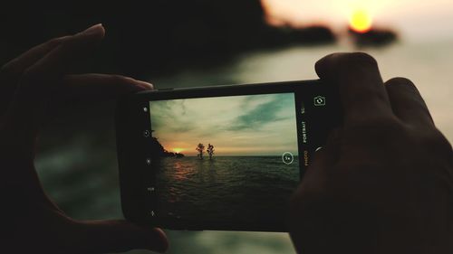 Cropped image of hand photographing through smart phone