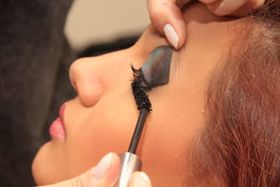 Close-up of beautician applying mascara on woman