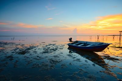 Boat moored on sea against sky during sunset