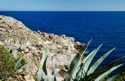 Scenic view of rocks by sea against sky