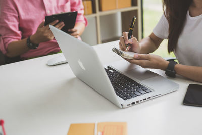 Midsection of woman using laptop on table